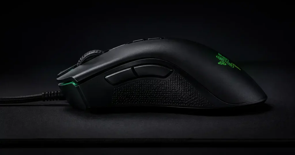 Black ergonomic gaming mouse side profile with green illuminated logo on a dark background